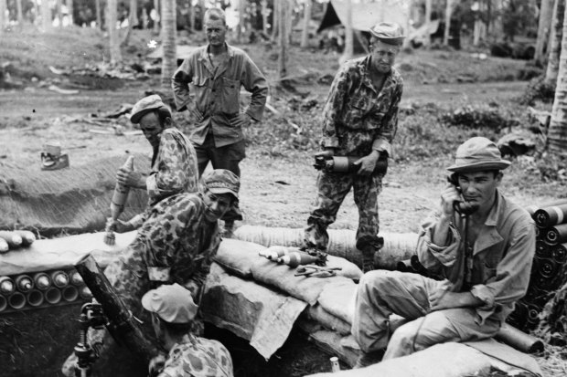 During World War II, soldiers fire a camouflaged gun during a barrage in the Solomon Islands.