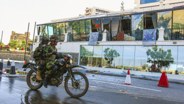 Sri Lankan soldiers ride past the bombed Kingsbury Hotel.