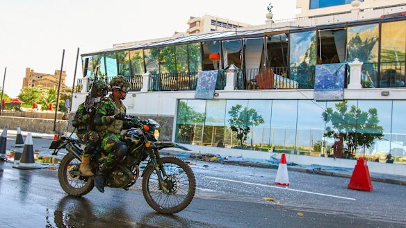 Sri Lankan soldiers ride past the bombed Kingsbury Hotel.