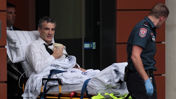 Terry McMaster leaves the Federal Court with the aid of paramedics after collapsing while being questioned.