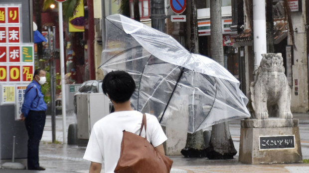 A man walks with an umbrella broken by strong winds in Naha, Okinawa.