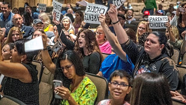 People hold signs and chant during a meeting of the North Allegheny School District school board meeting in McCandless, Pennsylvania. 