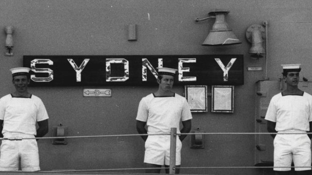 Sailors line the deck in front of 'Sydney' name plate. 