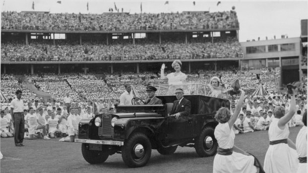 The Queen Mother, standing in a Land Rover, drives among the cheering school children on the Melbourne Cricket Ground