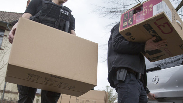 Police officers carrying boxes out of a house after a raid in Berlin, Germany.