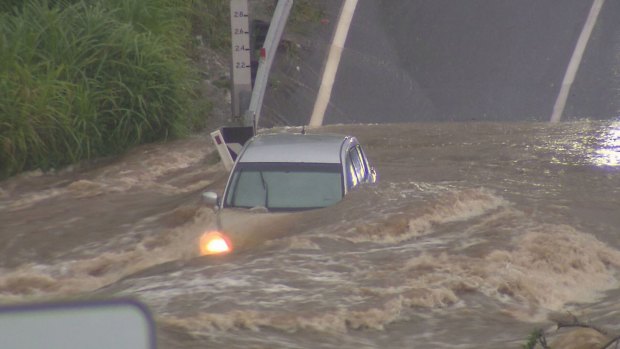 A car is overwhelmed by water while trying to cross a submerged road at the Gold Coast.