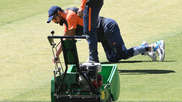 Virat Kohli inspects the Optus Stadium pitch.