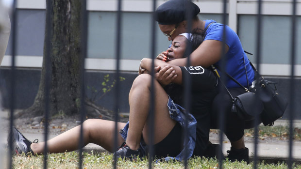 Two women cry outside the Stroger Hospital in Chicago on Sunday after they were asked to leave due to overwhelming crowds of family and friends of shooting victims. 