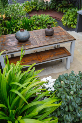 An outdoor table and bench seat with decorative handmade metal pots.