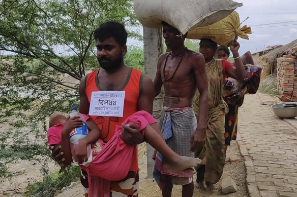 A disaster management volunteer carries a sick child as villagers on the Bay of Bengal coast are evacuated as a precaution against Cyclone Amphan in West Bengal, India, on Tuesday.
