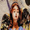 A woman takes a picture of the image “The Angel”, painted earlier this year by street artist Harry Greb, dedicated to journalists killed in Gaza, showing an angel wearing a bulletproof vest with the word “Press” written on it and holding the body of a child, in Rome, Monday, Aug. 25, 2025.