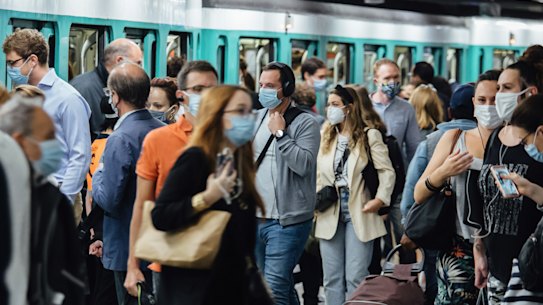 Morning rush hour commuters wear protective face masks while boarding and exiting a train at Saint-Lazare station in Paris this week.