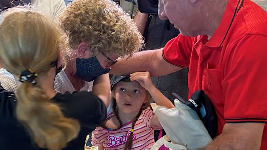 Jenny Hinde - ‘Mama’ - is hugged by granddaughters Annabelle, 10, and Elsie, 5, and husband of 40 years, Paul Hinde, after arriving from Melbourne on the second flight into Brisbane after borders reopened.