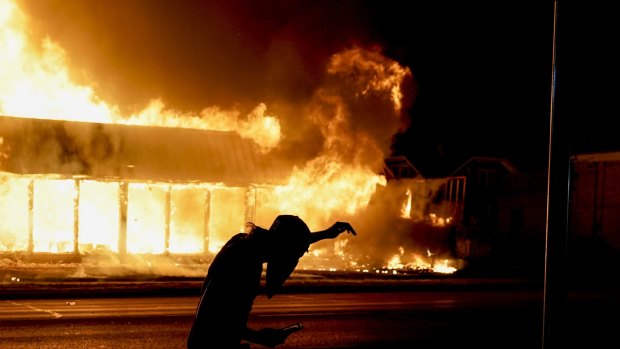 A protester walks past a building set on fire during protests against the police shooting of Jacob Blake in Kenosha on Monday.