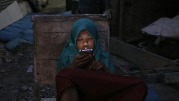 A girl checks her mobile phone at a slum in Jakarta. Poverty afflicts close to a tenth of Indonesia's nearly 270 million people. 