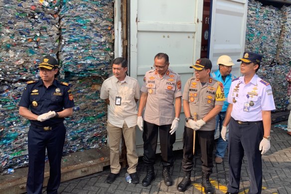 Indonesian police and customs officials display the contents of containers full of waste they say will be sent back to Australia.