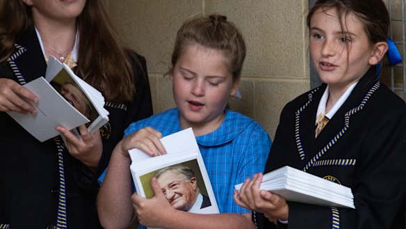Students hand out order of service cards at the memorial for John Elliott at Ikon Park. 