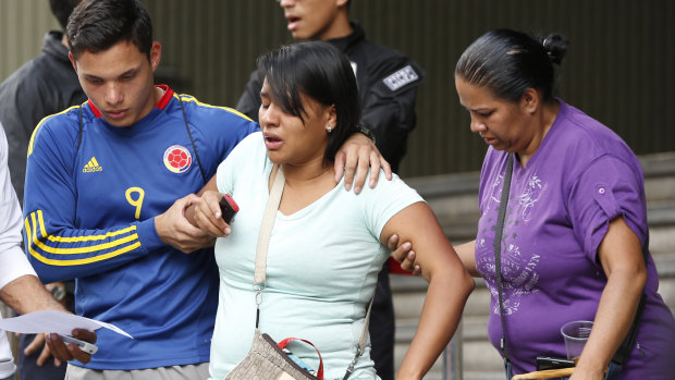 Barbara Barca, a survivor of the stampede at a crowded nightclub, is helped by relatives as they leave police headquarters in Caracas, on  Saturday.