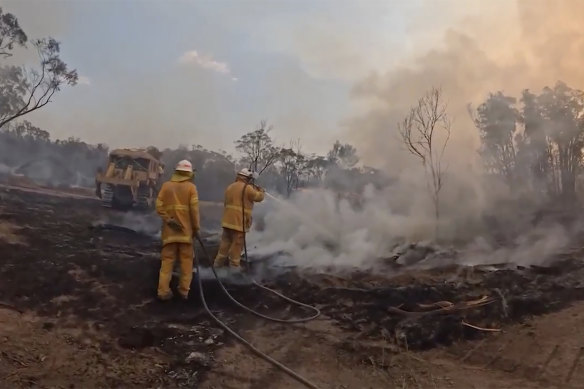 In this image made from video provided by the QFES, firefighters try to extinguish a wildfire in Tara on Tuesday. Firefighters have been battling the blaze for more than a week.