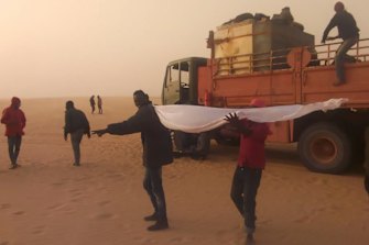 Migrants wait for help in the Libyan Sahara near the border with Sudan.  Authorities in southern Libya have accelerated expulsions of migrants to Sudan and Chad during the coronavirus pandemic. 