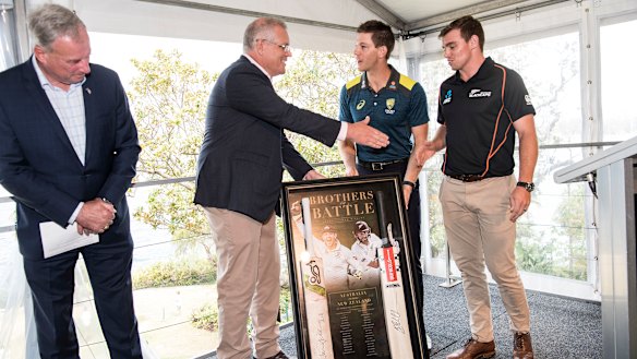 Prime Minister Scott Morrison accepts a gift from the Australian cricket captain Tim Paine and the Black Caps vice-captain Tom Latham at Kirribilli House.