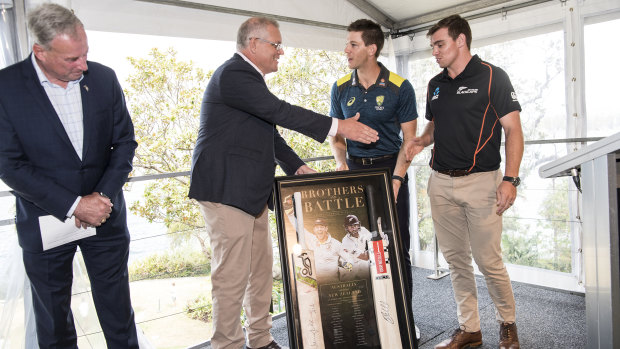 Prime Minister Scott Morrison accepts a gift from the Australian cricket captain Tim Paine and the Black Caps vice-captain Tom Latham at Kirribilli House.