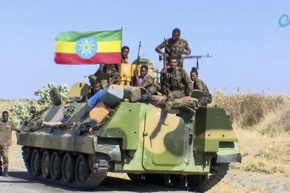 Ethiopian military sit on an armuored personnel carrier next to a national flag, on a road near the border of the Tigray and Amhara regions of Ethiopia.