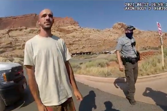 A police camera video still shows Brian Laundrie  talking to a police officer.