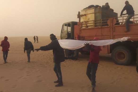 Migrants wait for help in the Libyan Sahara near the border with Sudan.  Authorities in southern Libya have accelerated expulsions of migrants to Sudan and Chad during the coronavirus pandemic. 