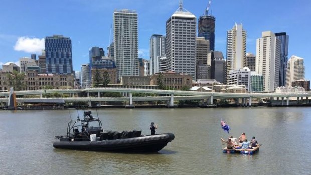 Five men float down the Brisbane River on a makeshift raft on Australia Day.