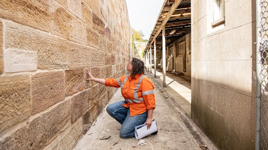 Rhian Jones, an archeologist at AMBS Ecology and Heritage, pointing to a filled-in sandstone block where the first time capsule was located.