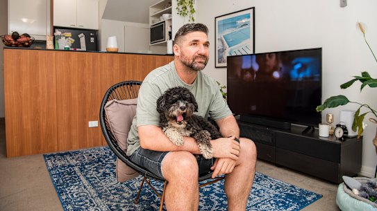 Michael Jermyn sitting on his Kmart outdoor chair with his dog George as he waits for months for his Nick Scali furniture to arrive.