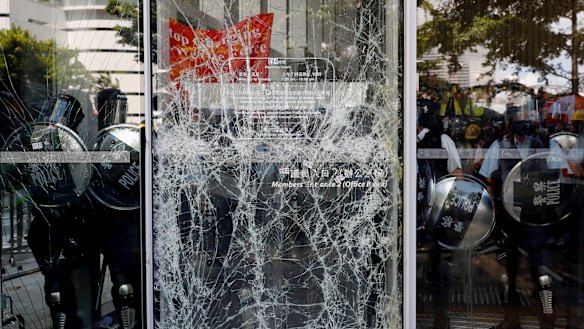 Police officers stand guard behind the cracked glass wall of the Legislative Council.