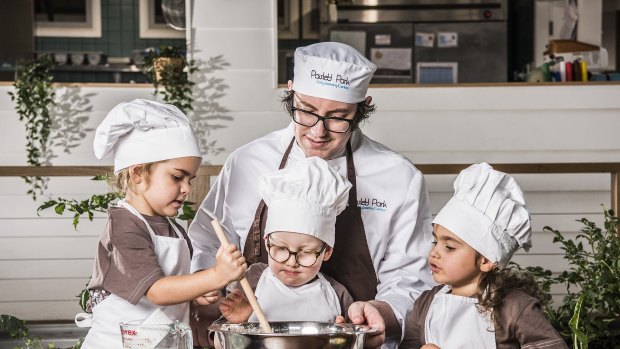 Jasmine, Billy and Gigi with chef Michael at Paisley Park Early Learning Centre Randwick, in an old bowling alley repurposed to bring the outside in, featuring plants, animals and a rock-climbing wall. 