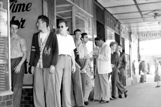 Bodgies lining up for haircuts. Hardly the most threatening sight.