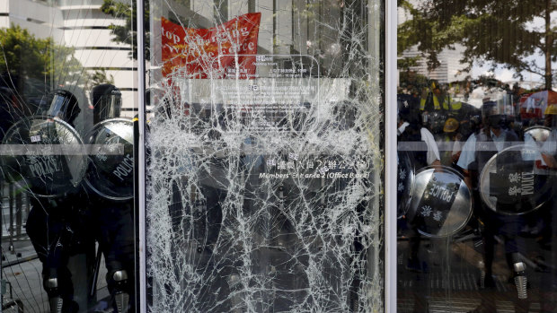 Police officers stand guard behind the cracked glass wall of the Legislative Council.