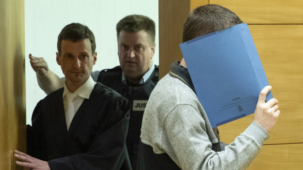 The 57-year-old defendant hides his face in the courtroom in Bielefeld, Germany.
