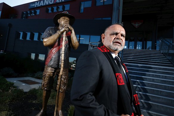 Essendon great Michael Long with his statue at the club’s headquarters.