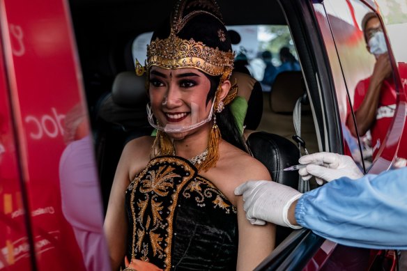 A woman wearing Javanese traditional costume receives a dose of the Sinovac (CoronaVac) vaccine at a drive-thru vaccination spot in a temple complex in Yogyakarta, Indonesia. 