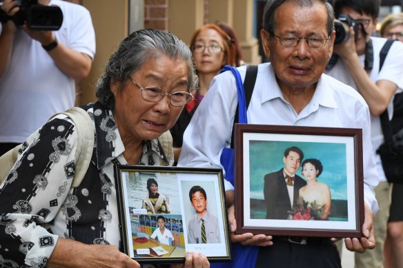 Min Lin's parents hold photos of their murdered relatives outside court in 2017.