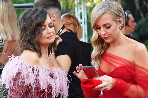 Lisa Wilkinson and Carrie Bickmore keep an eye on social media before launching on to the Logies red carpet last Sunday.