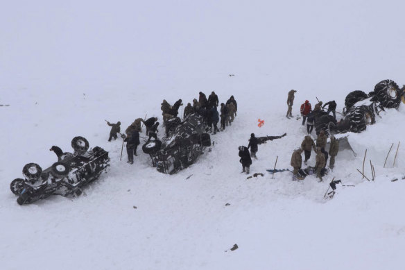 Rescuers dig in the snow around at least three overturned vehicles following the second avalanche.