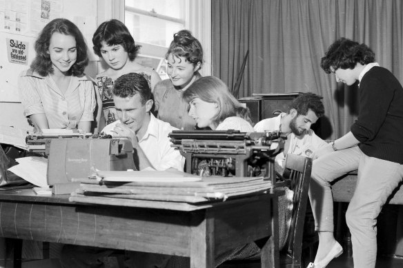 Clive James typing the University of Sydney's issue Honi Soit while, from left, Marie Taylor, Jane Iliff, Madeleine St John and Sue McGowan watch him as the editor, David Ferraro, and Helen Goldstein plan other pages on February 23, 1960.