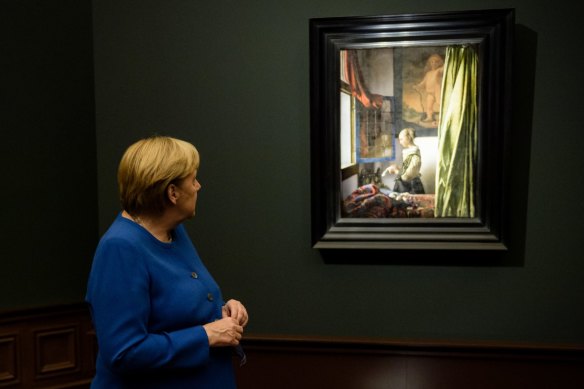 German Chancellor Angela Merkel looks at “Girl Reading a Letter at an Open Window”, in which a cherub has been recently revealed in the top-right corner. Experts deduced that it was painted over long after Vermeer finished with the work.