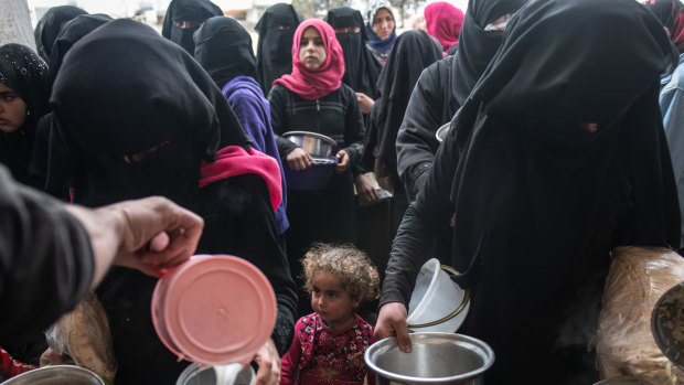 Displaced Syrians wait for hot meals in Idlib.