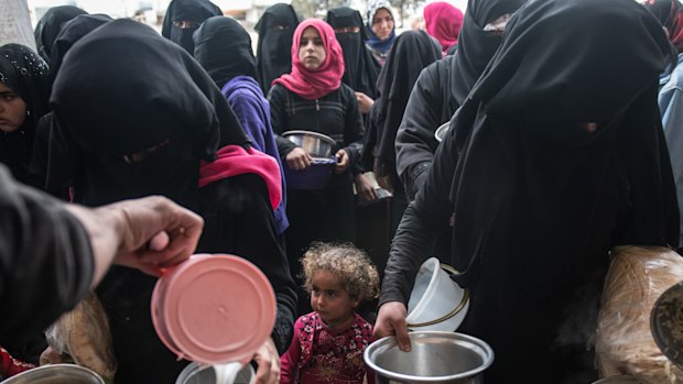 Displaced Syrians wait for hot meals in Idlib.