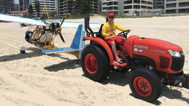 The stricken glider is towed off the beach by surf lifesavers on Saturday.