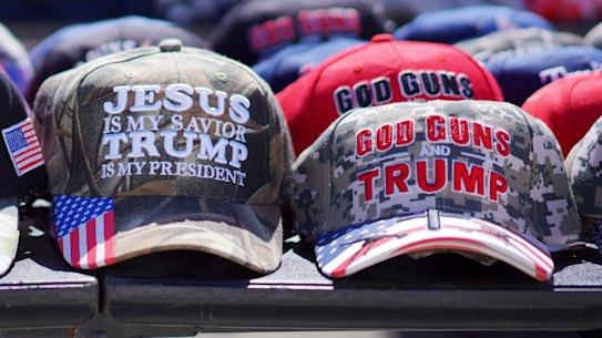 Hats reading, “God, Guns and Trump” and “Jesus is my saviour, Trump is my president” are sold at a campaign rally.