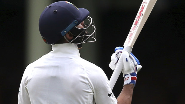 Back to the pavilion: Virat Kohli looks at his bat after being dismissed by Hardie.