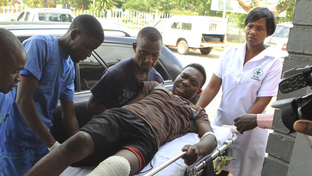 An injured man is helped at a private hospital after an alleged assault by a group of uniformed soldiers.